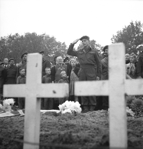 Photo d'un major en uniforme faisant le salut militaire devant la tombe d'un soldat, alors qu'on aper�oit � l'avant-plan deux grandes croix blanches, � Ossendrecht (Pays-Bas), le 26 octobre 1944.
