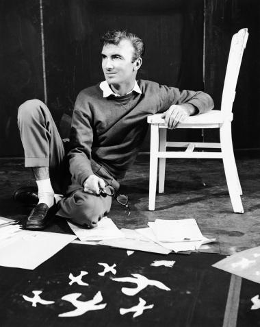 Norman McLaren during a photo session with some of his ongoing projects spread out around him.